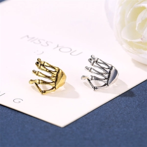 Detailed close-up of punk style skull hand ear cuffs in gold and antique silver finish