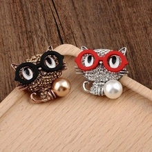 Detailed view of gold and silver cat brooches with rhinestones on a wood tray