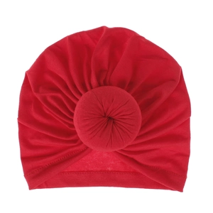 Close-up of bright red baby beanie featuring a 3D donut knot and soft ribbed fabric