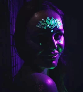 Glow-in-the-dark face jewels on a model for music festivals and night parties