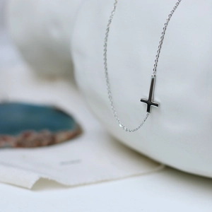 Polished silver horizontal cross necklace in stainless steel on minimalist background