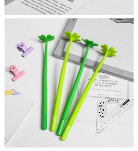 Flat lay view of four green lucky clover pens with soft silicone leaf tops on a white desk