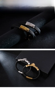 Detail of men's braided leather bracelet with gold and silver lion head metal clasps