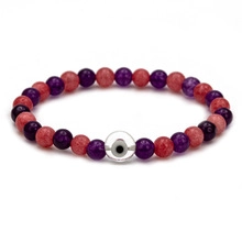 Detail of beaded bracelet with red and purple crystals and metallic evil eye charm