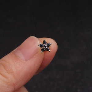 Macro shot of silver flower helix stud earring featuring five dark faceted crystals