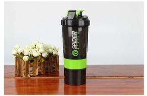 Détail d'un shaker à protéines noir avec couvercle vert posé sur une table en bois