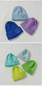 Detailed knit texture and color variety of rib-knit beanies with embroidered smiley faces