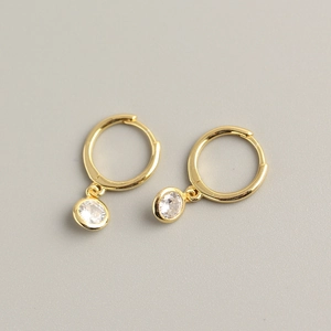 Detailed view of gold hoop earrings with bezel-set round cubic zirconia drops