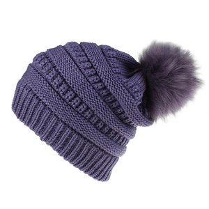 Detail der tiefvioletten Strickmütze mit Kunstfell-Pompon und dickem Zopfstrickmuster