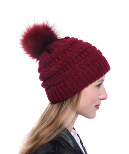 Detailansicht der weinroten Strickmütze mit Zopfmuster und flauschigem Bommel