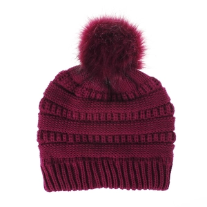 Detail einer burgunderroten Strickmütze mit flauschigem Kunstfell-Bommel und Rippenmuster