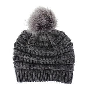 Details der Stricktextur und flauschiger Kunstpelz-Pompon an dunkelgrauer Strickmütze
