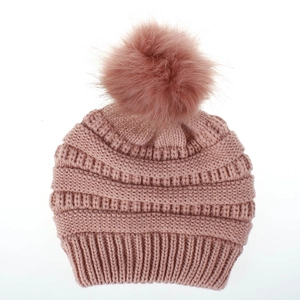 Nahaufnahme einer rosa Strickmütze mit großem Kunstpelz-Bommel und gerippter Textur