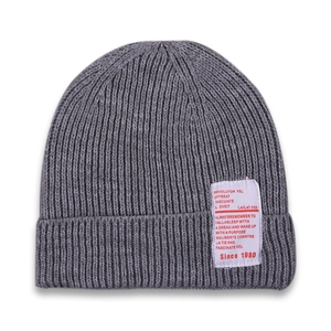 Detail of grey ribbed knit beanie for kids with white fashion label on white background