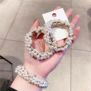 Close-up of white pearl elastic hair ties shown as bracelets on wrist and card
