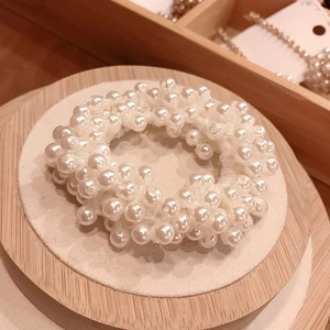 Close-up of elegant white imitation pearl hair tie on a wooden display stand