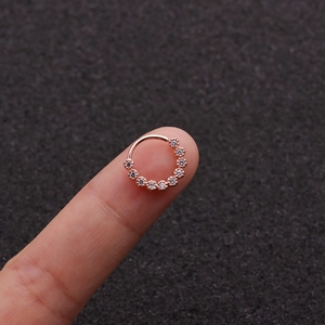 Macro shot of rose gold geometric nose ring with zircon crystals held by hand