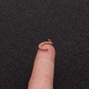 Rose gold geometric nose ring with zircon stones shown on fingertip for size scale