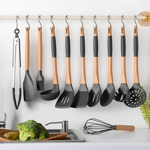 11-piece silicone kitchen utensil set with wooden handles hanging on hooks in a modern kitchen