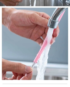 Pink silicone straw cleaning brush being rinsed under running water after camping use