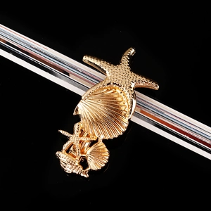Close-up of golden starfish and seashell hair clip with detailed metallic textures