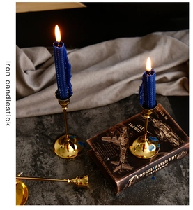 Detailed close-up of golden iron candlestick holder on grey marble with blue candles