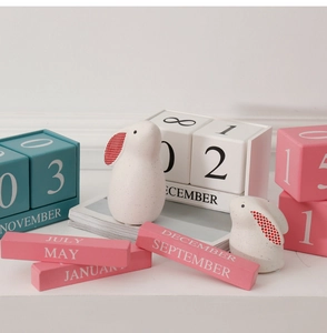Détail d'un calendrier perpétuel en bois avec lapins et blocs colorés style Morandi