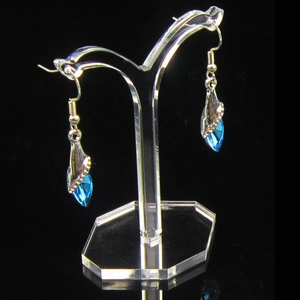 Blue teardrop crystal earrings hanging on a transparent acrylic jewelry display stand