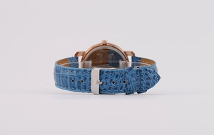 Detail of deep blue embossed leather strap with rose gold case and silver metal buckle
