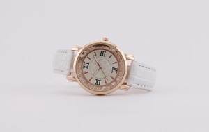 Close-up of rose gold watch with sparkling crystals and white crocodile leather strap