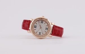 Close-up of rose gold watch case with sparkling crystals and red crocodile leather strap