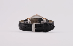Detail of black crocodile texture leather strap and polished metallic watch buckle