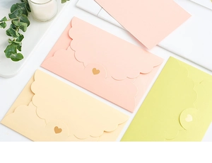 Detail of scalloped edge envelopes with heart cutout closure in pastel colors