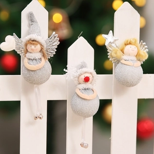 Detail of glittery Christmas angel and snowman ornaments hanging on a white fence