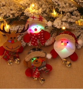 Close-up of four glowing plush Christmas ornaments with bells on a festive background