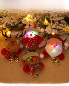 Close-up of LED glowing Christmas plush pins with Santa, reindeer, and bells on linen