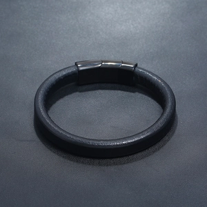 Close-up of black leather bracelet with magnetic metal clasp on a textured surface