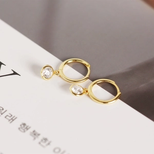 Macro shot of gold hoop earrings with suspended clear round zircon pendants