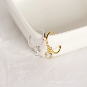 Detail of S925 silver hoop earrings with round zircon charms in gold and silver finish