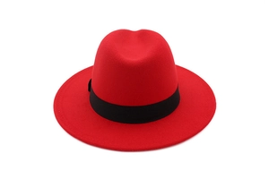 Top view of a red wool fedora hat with a black ribbon band on a white background