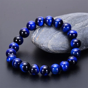Close-up of natural blue tiger eye beads with cat-eye effect on a grey stone base