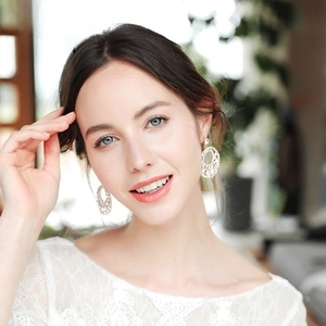 Primo piano di un ear cuff floreale in argento con strass e perle su una modella