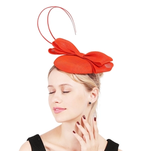 Detail of red fascinator hat with elegant mesh bow and curved ribbons for formal events
