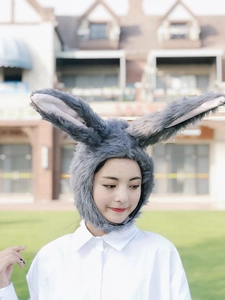 Detailed view of plush rabbit ear headband in gray worn by a model in outdoor setting