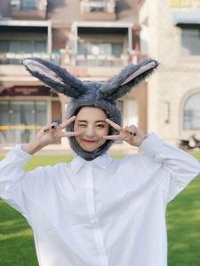 Detail of grey plush rabbit ear hat worn by a model in an outdoor scenic setting