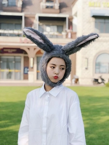 Detail of grey plush long rabbit ear hat worn by a model in outdoor natural light setting