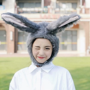 Cute plush grey bunny ear hat accessory worn by a model in a natural outdoor setting