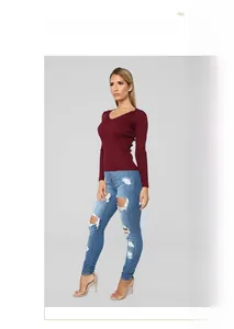 Full body shot of a model wearing high-waisted distressed skinny jeans and red knit top
