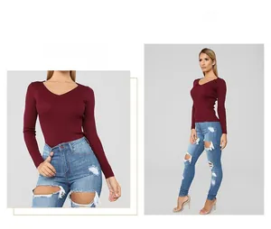 Detail of ripped light blue jeans paired with a burgundy V-neck ribbed knit long sleeve top