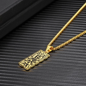 Detail view of gold rectangle pendant with engraved black runes on a box chain necklace